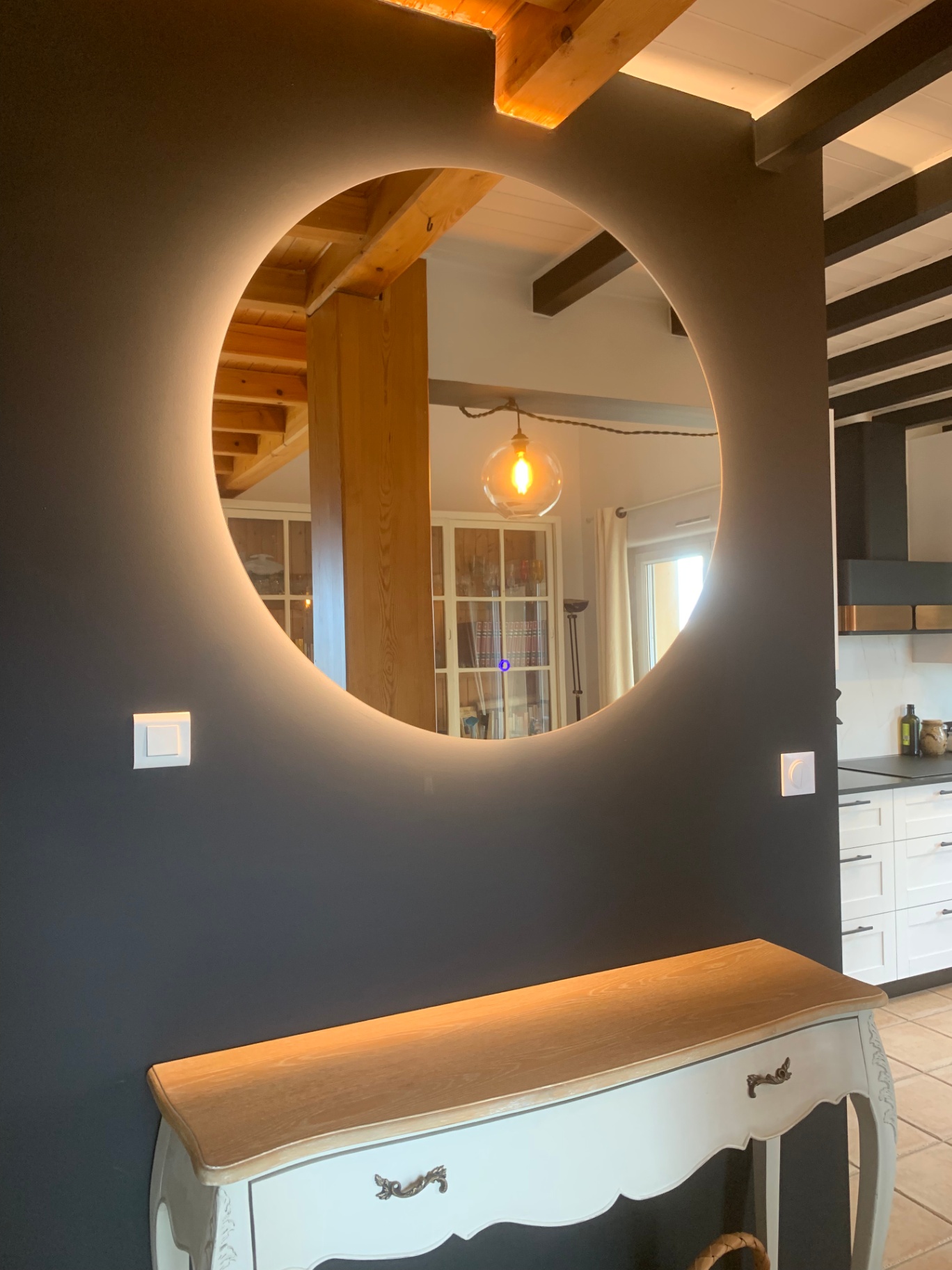 Miroir rond rétroéclairé sur mur foncé